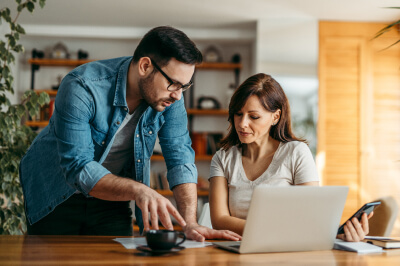 Couple at home discusses what a loan level price adjustment is while sitting at computer.