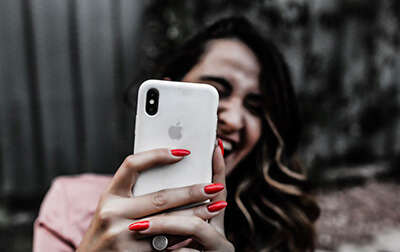 A woman holding up a phone to take a photo, the phone in focus.