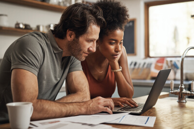 Couple researched renting out their primary residence together on a laptop.