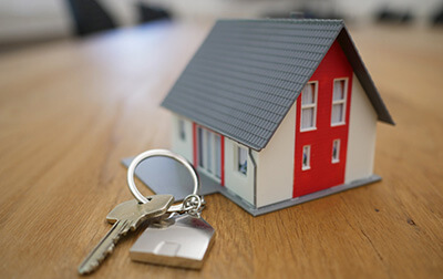 House keys on a table along with a small toy home.