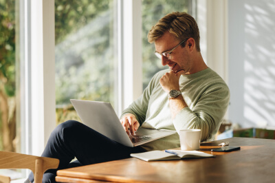 Man uses laptop to find the right home in his real estate housing search.