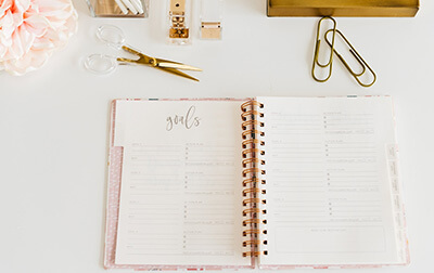 A open planner on a desk along with other office supplies.