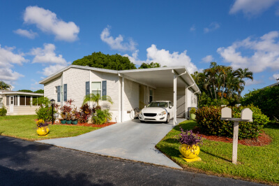 Outside of manufactured home with a car sitting in carport.