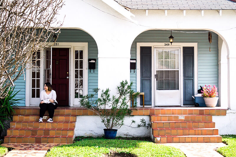 A first time homebuyer sitting on the porch of her home purchased with a FHA loan