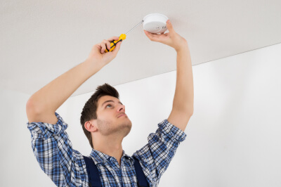 Man checks fire alarm for home safety.